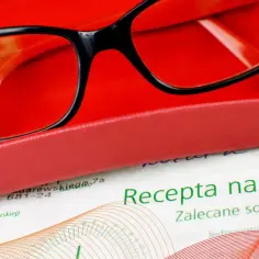 Okulary w etui, obok recepta na okulary. Optometrysta może wystawić receptę na okulary, potwierdzając to dokument.