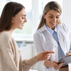 Lekarka omawia z pacjentką czego nie wolno po laserowej korekcji wzroku, wskazując na dokument.