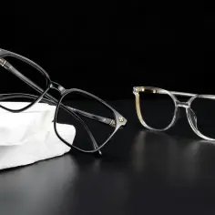 Dwa stylowe okulary, czarne i transparentne, leżą obok siebie. Zastanawiasz się, czy można przełożyć szkła do innych oprawek?