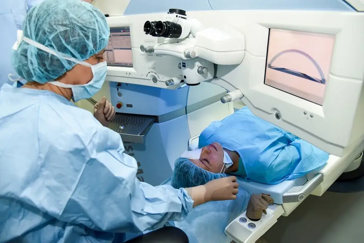 Chirurg przygotowuje się do operacji zaćmy drugiego oka. Pacjent leży pod laserem, a na ekranie widoczny jest obraz oka.