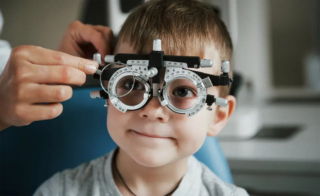 Chłopiec z refrakcyjnym aparatem na oczach. Czy wada wzroku plus może się cofnąć? Badanie wzroku u optometrysty.