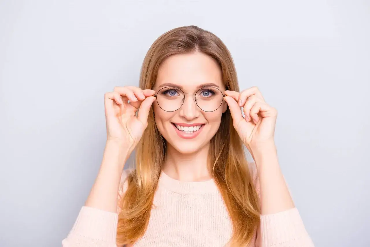 Uśmiechnięta blondynka w okularach jednoogniskowych, co to znaczy? To okulary do korekcji jednej wady wzroku, np. krótkowzroczności.