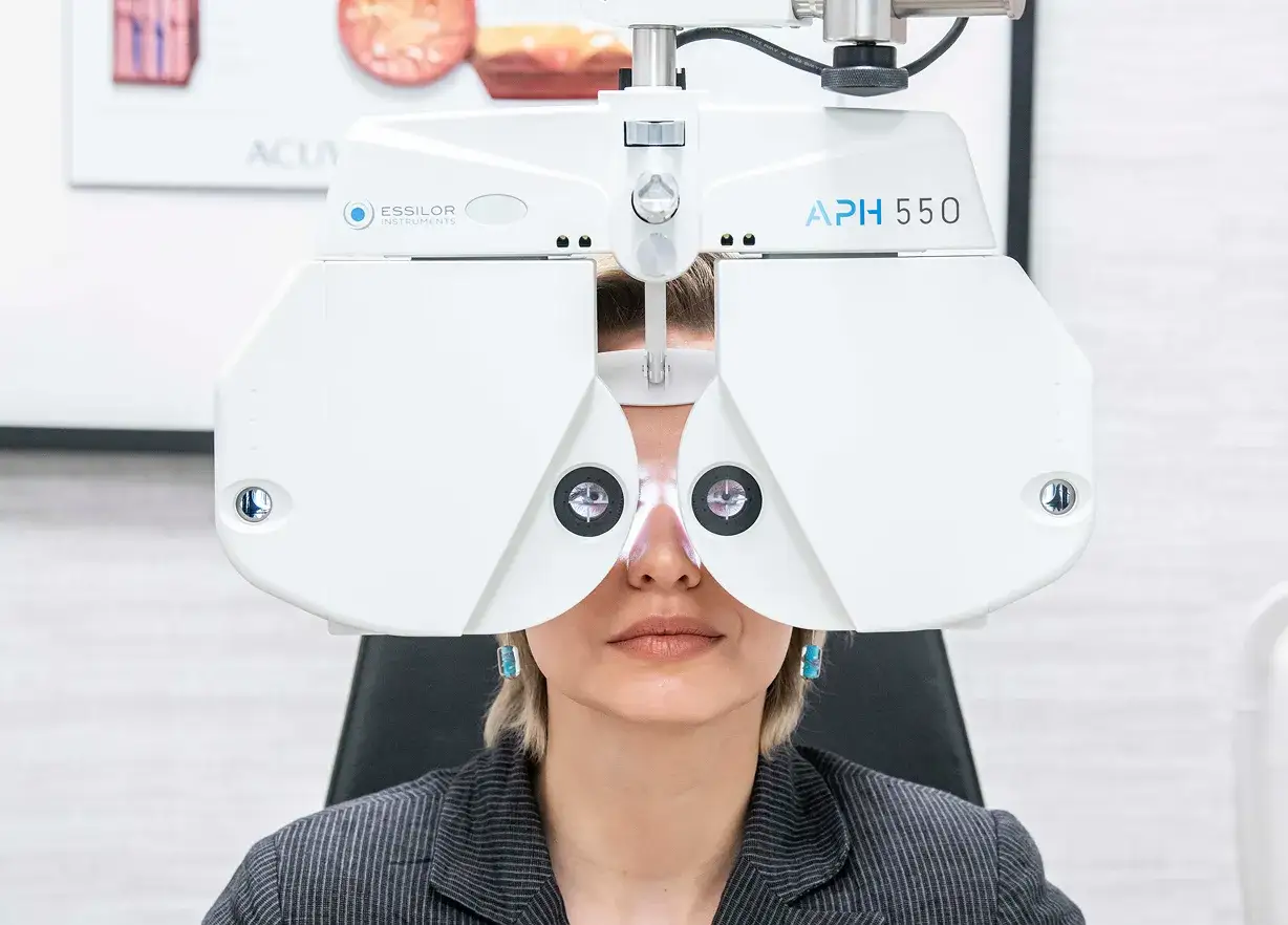 Kobieta poddawana badaniu wzroku na foropterze. To pokazuje, co to jest optometrysta i jak dba o nasze oczy.