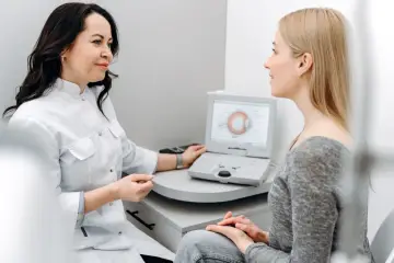 Lekarka omawia z pacjentką laserową korekcję wzroku po 50 roku życia, analizując wyniki badań na ekranie.